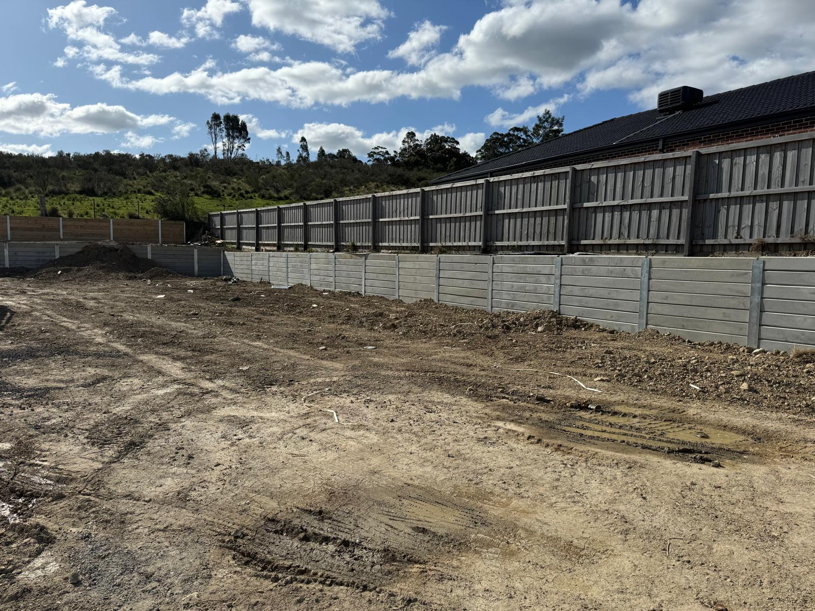 A levelled block beside a finished concrete sleeper retaining wall